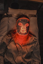 vrouw op bed met facelite LED masker op rood licht
