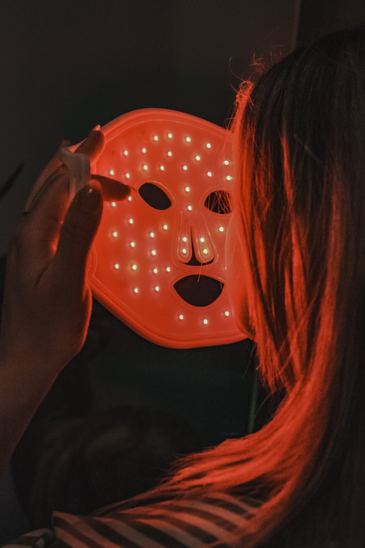 Vrouw die LED masker aandoet
